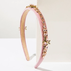 Close-up of pink velvet headband with rhinestones and gold bee insect charm detail