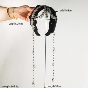 Détail d'un serre-tête noir de style ethnique avec breloques en métal et longs glands