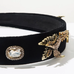 Detail of velvet headband featuring a golden dragon emblem and sparkling crystal centerpiece