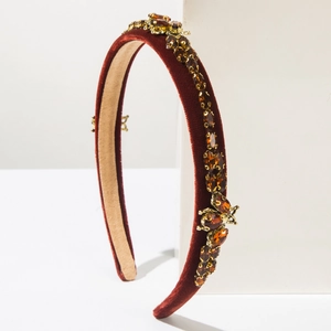 Close-up of red velvet headband with amber rhinestones and ornate insect details