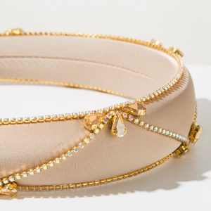 Detailed macro view of luxury champagne satin headband with inlaid rhinestones and amber gems