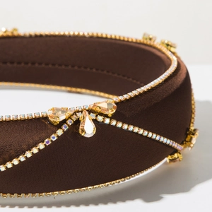 Macro view of brown satin headband with golden rhinestone chain and champagne zircon bow