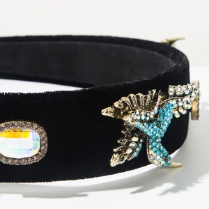 Macro view of velvet headband with crystal eagle and colorful gemstone inlay detail