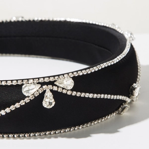 Close-up of black satin headband with sparkling rhinestones and crystal bow details