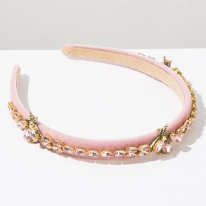 Detail of pink velvet headband with inset crystals and golden bee accents for party wear