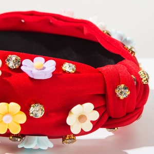 Detailed close-up of red fabric headband with colorful floral 3D ornaments and crystals