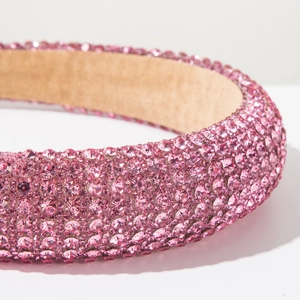 Gros plan d'un serre-tête en cristal rose montrant les strass et la doublure intérieure