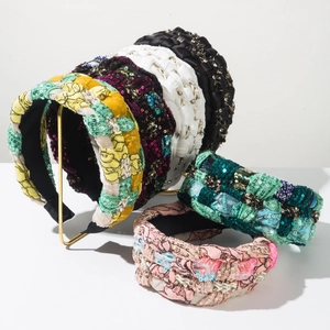 Close-up of wide braided headbands with sparkling sequins and embroidery details