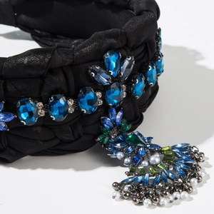 Détail d'un serre-tête noir vintage avec gemmes bleues et pendentif à pampilles chic