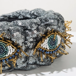 Detail der Perlen-Evil-Eye-Anhänger mit Goldröhren auf einem silbernen Pailletten-Stirnband