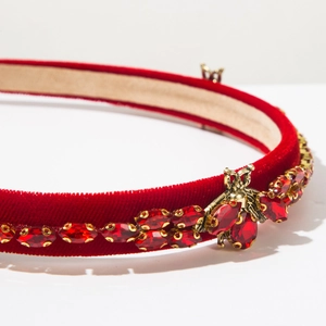 Close-up of red velvet headband with golden metal bee and sparkling rhinestones
