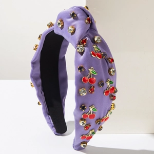 Vue détaillée du serre-tête en satin violet avec strass brillants et breloques cerise