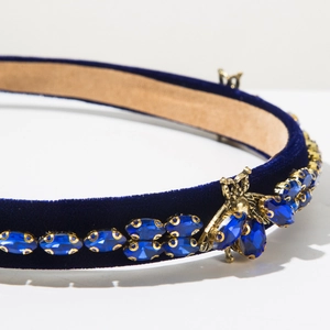 Detailed close-up of velvet headband with blue crystals and golden bee embellishment
