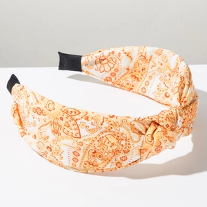 Detail of bohemian extra-wide paisley fabric headband with a stylish top knot design