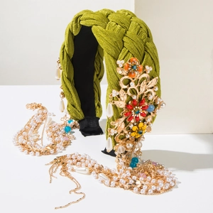 Nahaufnahme von grünem Haarreif mit goldenen Blumen und Fransen aus Perlenketten