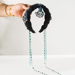 Détail d'un serre-tête vintage avec strass bleus et longues chaînes à pompons verts