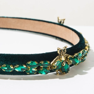 Close-up of luxury dark green velvet headband with rhinestones and gold bee detail