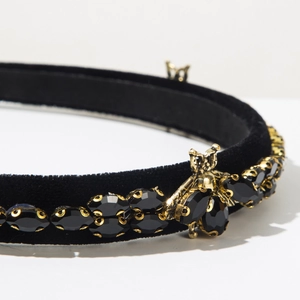 Detail of velvet headband featuring intricate gold bee motif and faceted black rhinestones