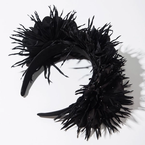 Vue détaillée de fleurs en tissu noir aux bords plumeux sur un serre-tête de style gothique