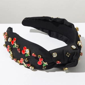 Détail d'un serre-tête en tissu noir orné de cerises émaillées rouges et de strass