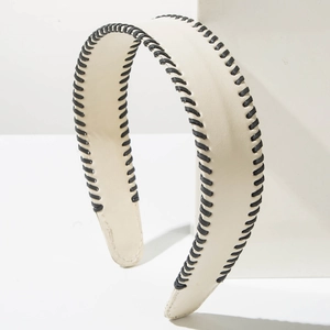 Detail of cream leather headband with black whipstitch stitching on minimalist background