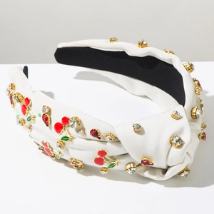 Détail d'un serre-tête noué blanc avec breloques cerises rouges et strass scintillants