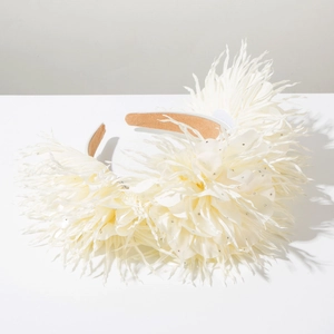 Gros plan d'un serre-tête fleurs blanches avec plumes, pétales en tissu et cristaux