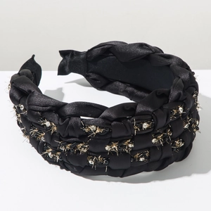 Detailed macro view of black woven headband with gold metallic wire and rhinestone accents
