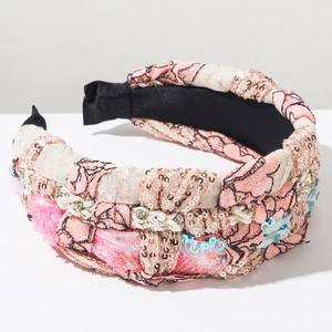 Detail of pink braided headband with sequins, pearls and crystals on white background