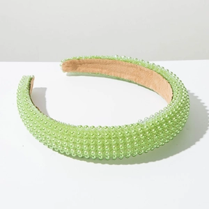Close-up of light green imitation pearls on a thick padded headband with velvet lining