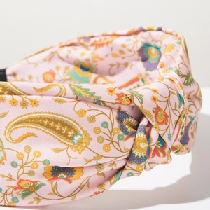Detailed macro view of pink paisley fabric knot headband with colorful floral patterns