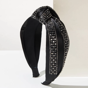 Macro detail of black satin headband with top knot design and sparkling rhinestone accents