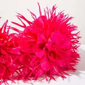 Détail macro de deux accessoires de cheveux fleurs en tissu rouge rose avec petits strass argentés