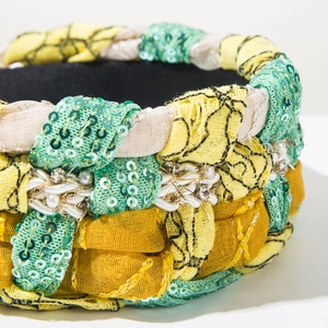 Macro detail of braided bohemian headband with yellow fabric, sequins, and pearls