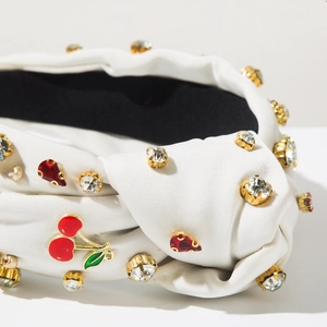 Vue détaillée du serre-tête en satin blanc avec breloques cerise et cristaux rouges