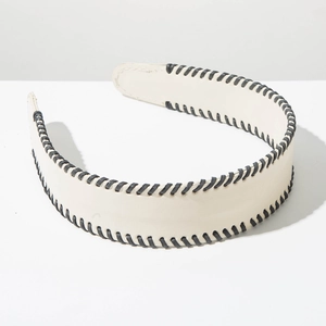 Close-up of wide cream leather headband featuring contrast black whipstitch edge detailing