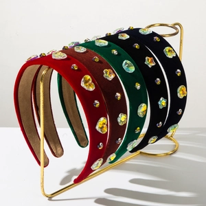 Close-up of velvet padded headbands with colorful crystals hanging on a gold display stand