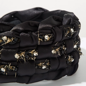 Macro view of black braided headband with white rhinestones and gold thread detail