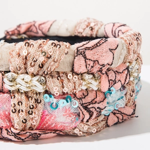 Macro detail of bohemian braided headband with pink floral embroidery and gold sequins