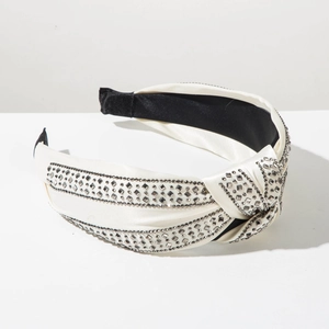 Detailed view of white satin knotted headband with three rows of sparkling grey rhinestones