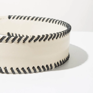 Macro detail of cream leather headband featuring decorative black whipstitch edge