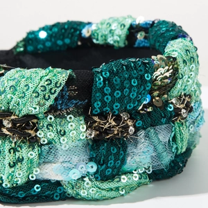 Macro shot of green sequin woven headband with crystal accents and braided texture