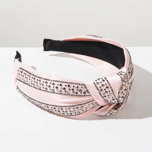 Detail of pink satin headband featuring a knotted design and five rows of grey rhinestones