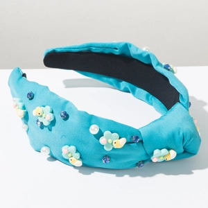 Dettaglio del cerchietto in tessuto verde acqua con fiori blu, perle e strass lucidi