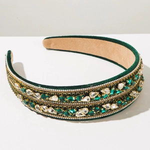 Détail d'un serre-tête en velours vert avec cristaux émeraude et perles dorées tressées