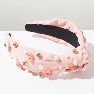 Dettaglio di fascia annodata rosa con perle bianche e decorazioni in strass scintillanti
