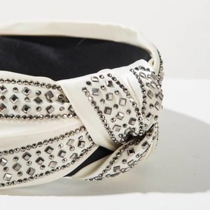 Close-up of white satin knotted headband with inlaid silver square and round rhinestones
