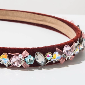 Detailed view of burgundy velvet headband featuring luxury crystals and mesh bow décor