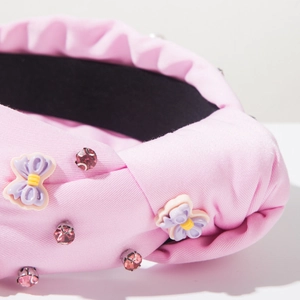Dettaglio fascia rosa annodata con strass scintillanti e ciondoli a farfalla