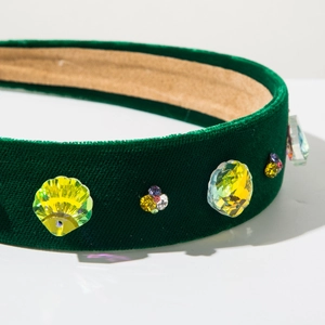Detail of dark green velvet headband with shell-shaped crystals and colorful gems